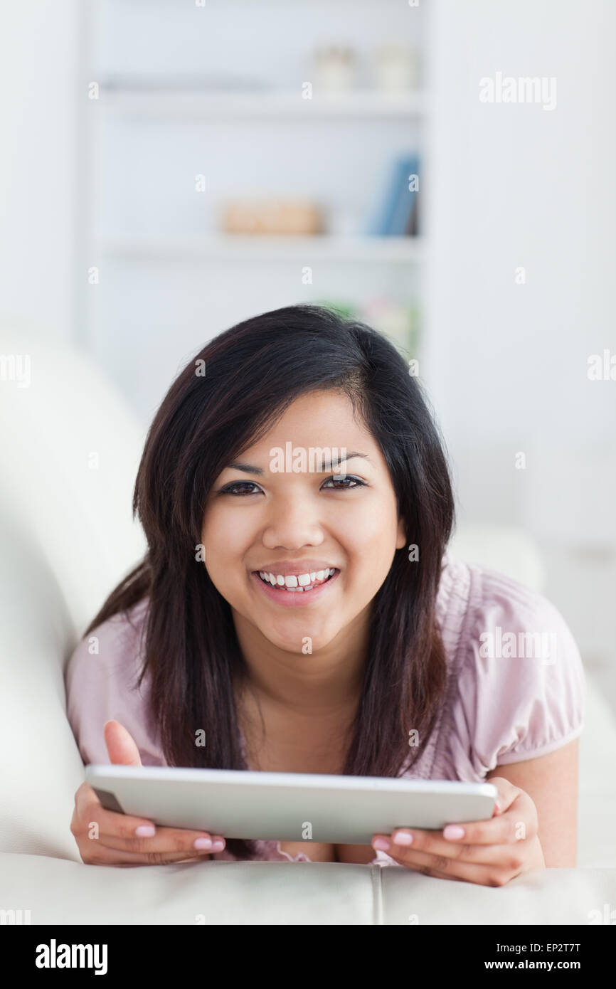 Smiling woman lying on a sofa while holding a tablet Stock Photo - Alamy