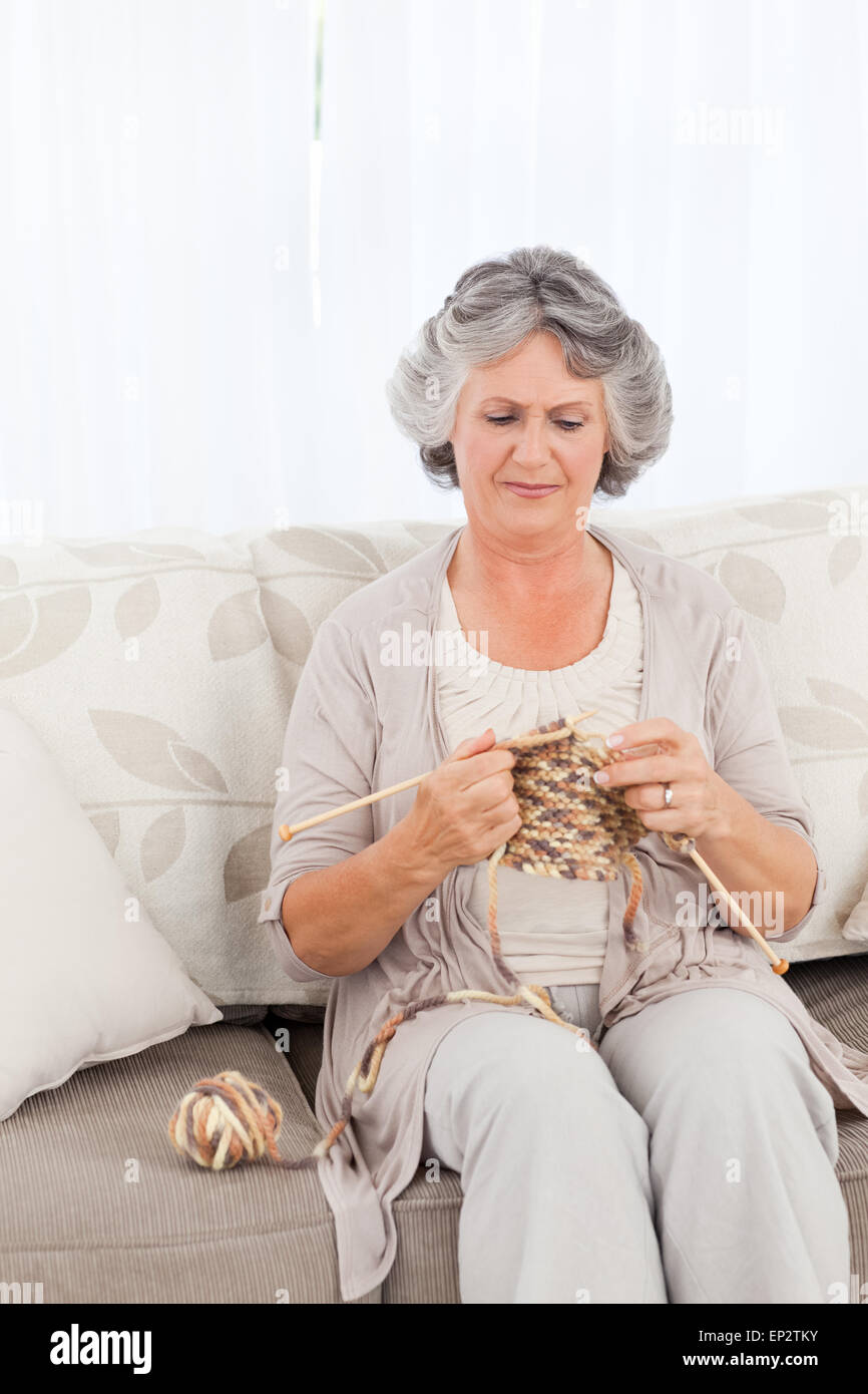 Senior woman knitting on her sofa Stock Photo - Alamy
