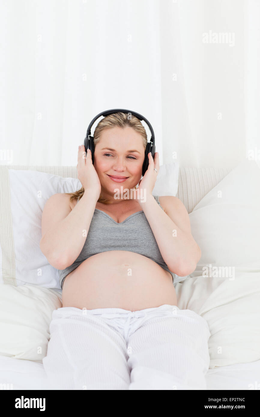 Lovely pregnant woman listening to music on her bed Stock Photo - Alamy