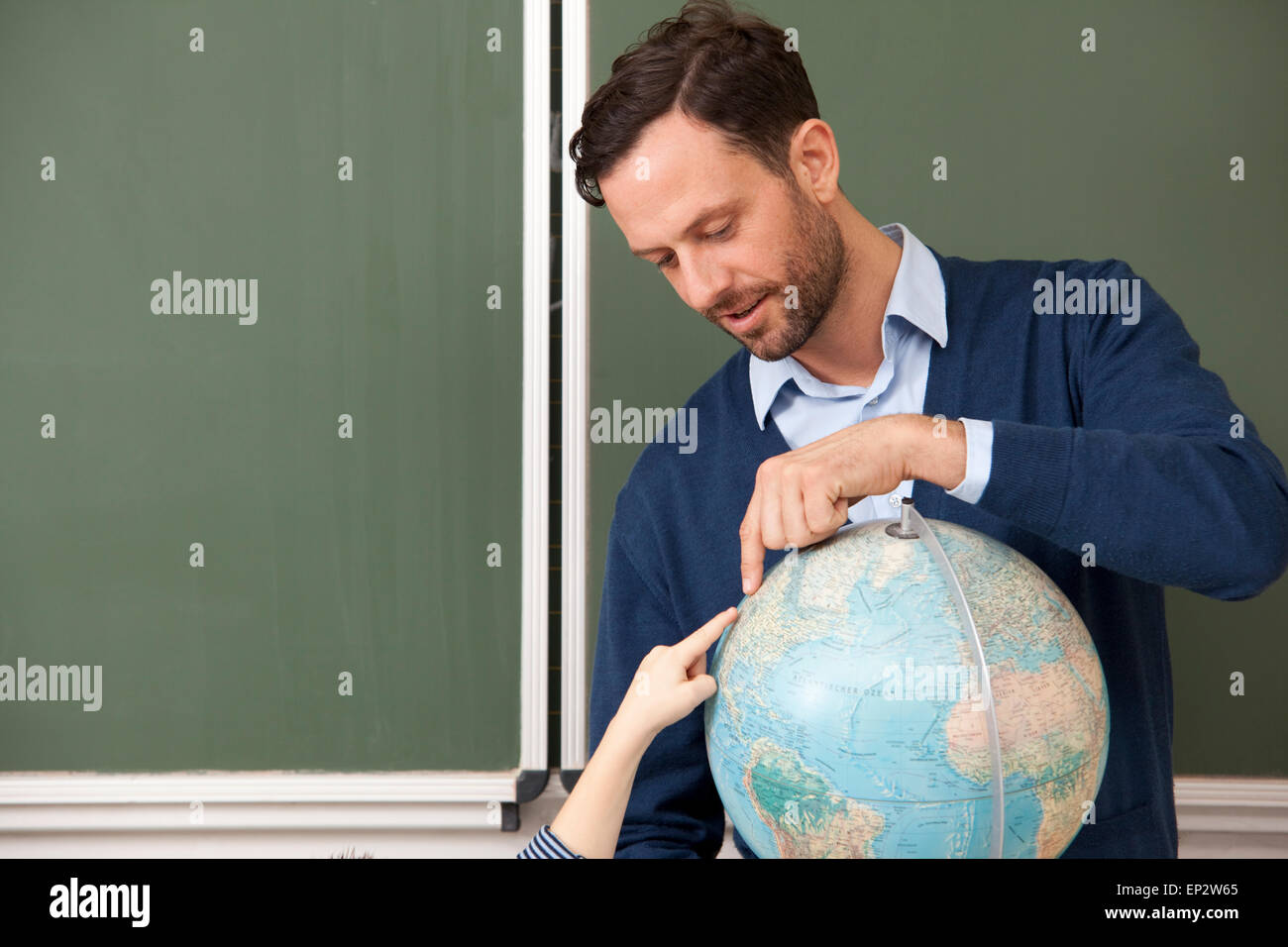 Teacher and pupil pointing at globe in classroom Stock Photo - Alamy