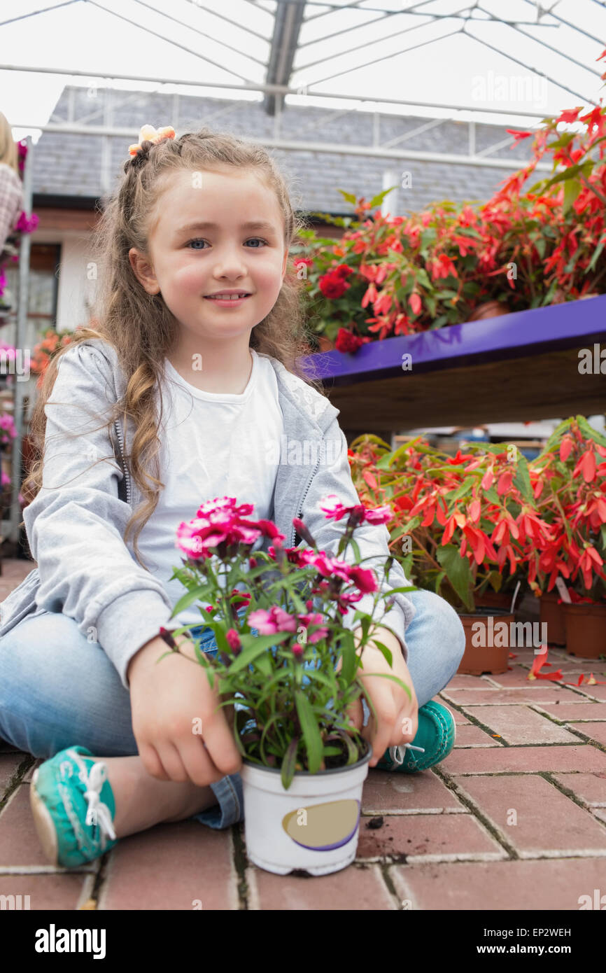 Little girl sitting on the path with a flower Stock Photo