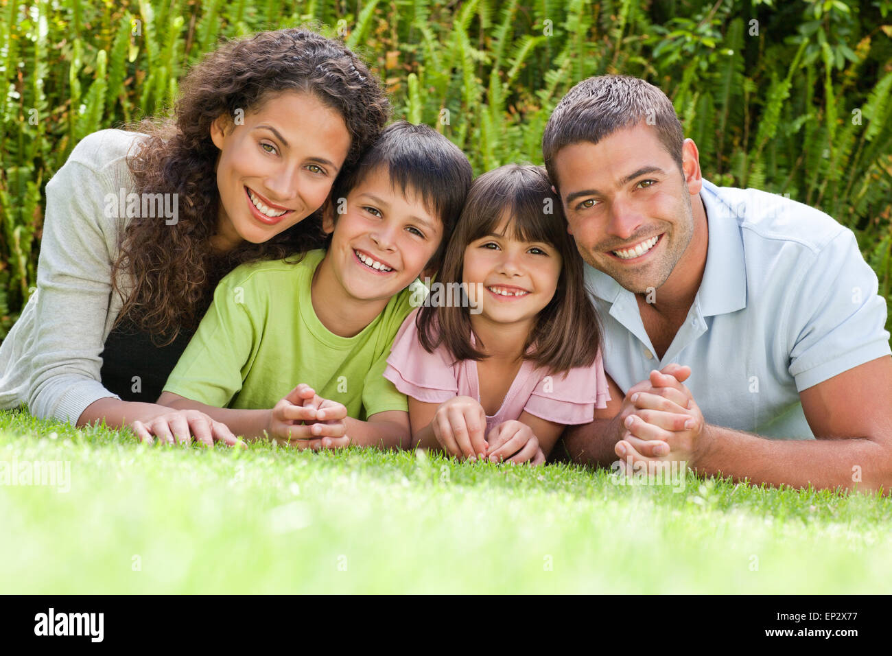 Happy family lying down in the garden Stock Photo - Alamy