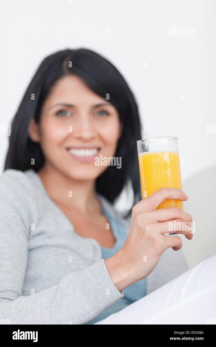 Woman smiling while holding a glass of orange juice Stock Photo - Alamy