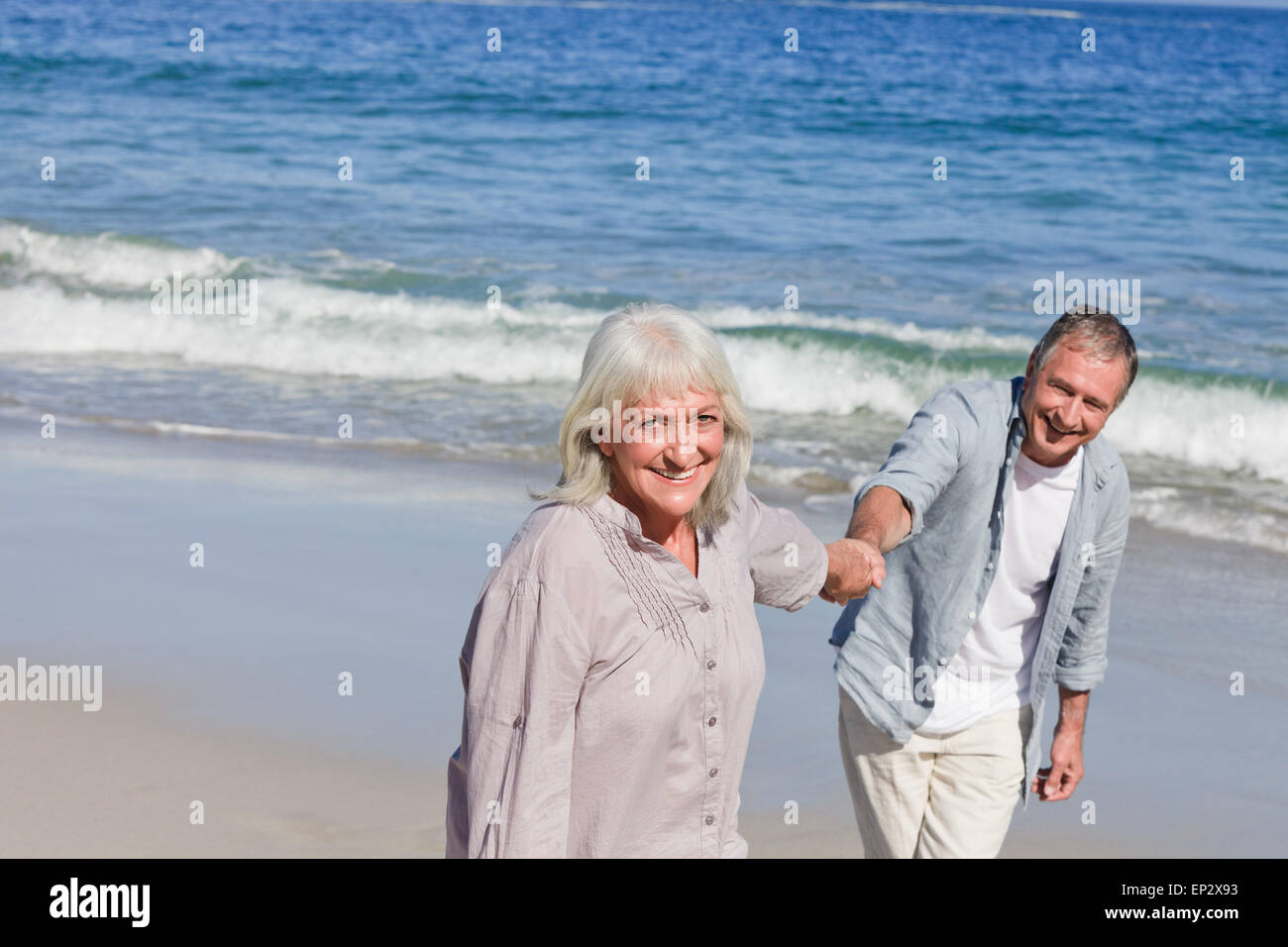 Elderly couple walking on the beach Stock Photo - Alamy