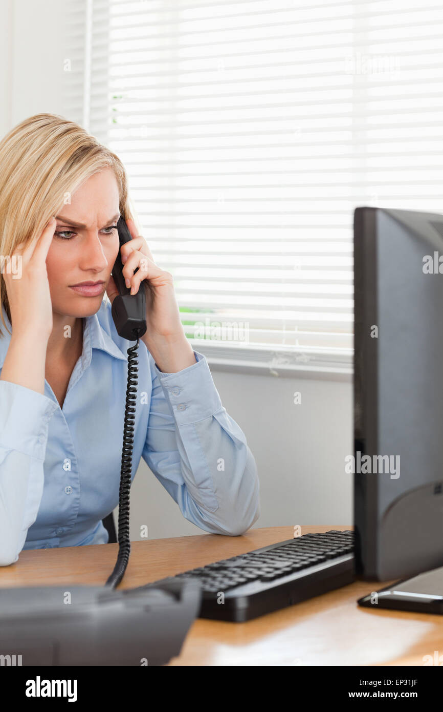 Businesswoman on phone looking at screen while having headache Stock