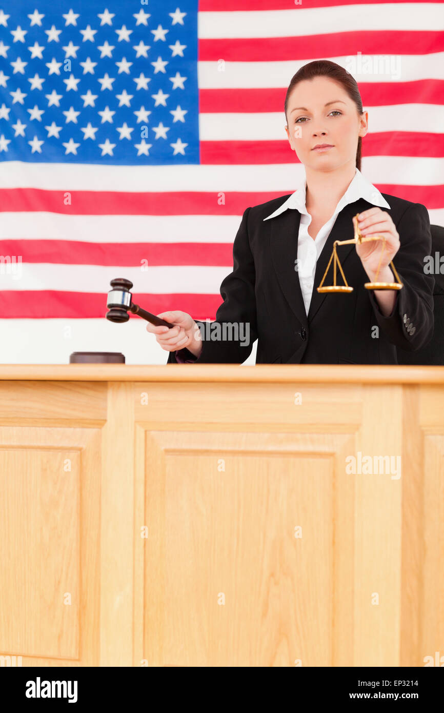Young judge knocking a gavel and holding scales of justice Stock Photo