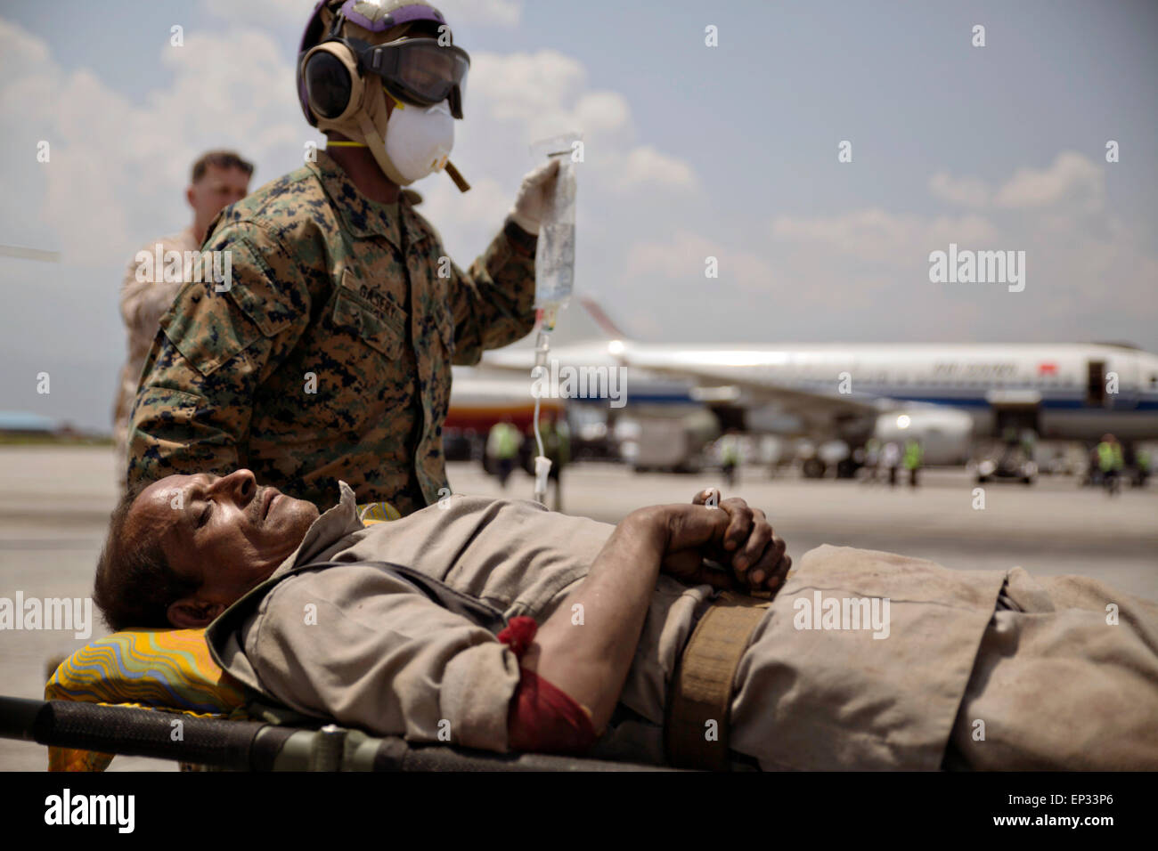 Kathmandu, Nepal. 13th May, 2015. A U.S. Marine helps carry a Nepalese man to a triage area at the Tribhuvan International Airport May 12, 2015 in Kathmandu, Nepal. A 7.3 magnitude aftershock earthquake struck the kingdom following the 7.8 magnitude earthquake on April 25th. Stock Photo