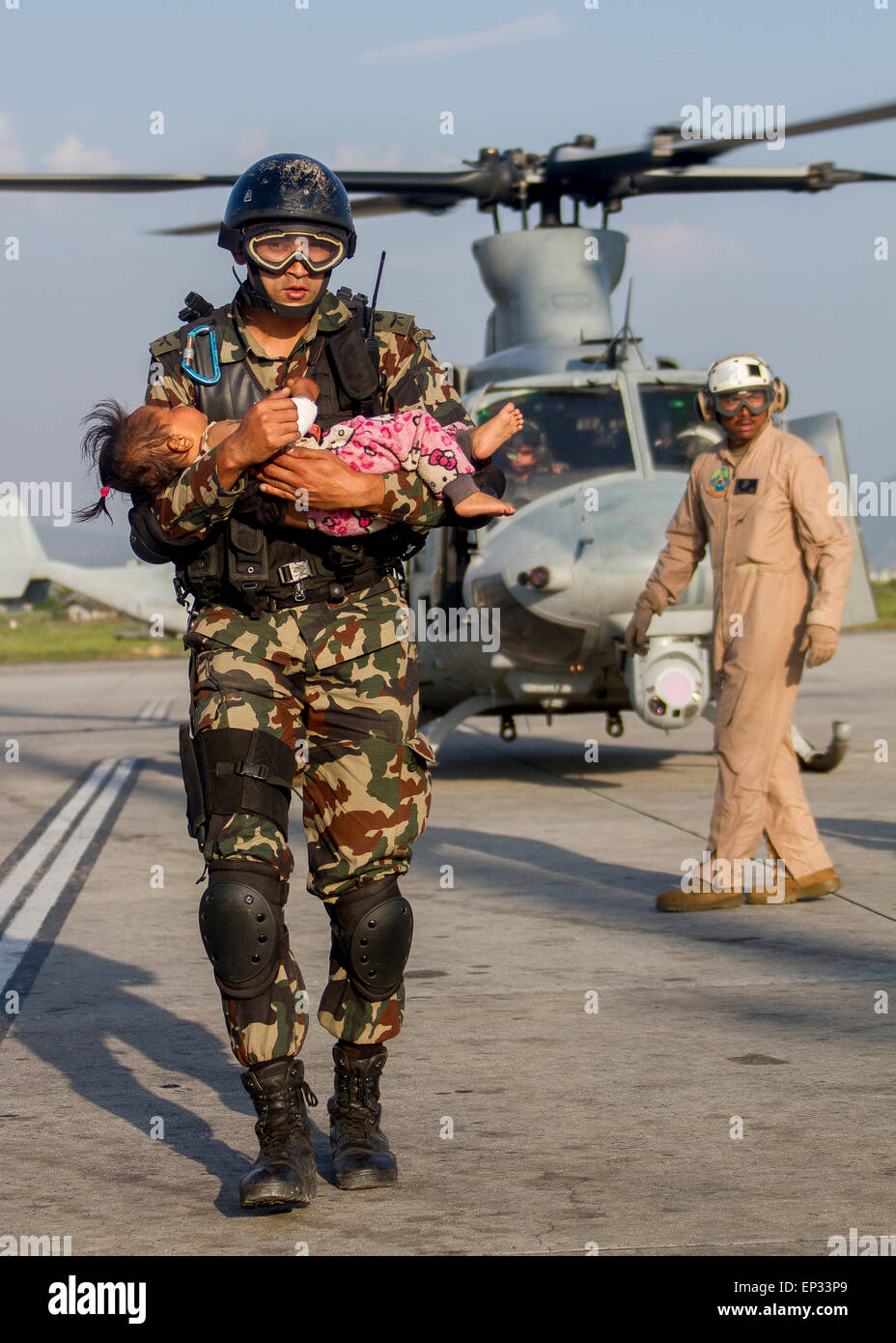 Kathmandu, Nepal. 13th May, 2015. A Nepalese soldier carries a young earthquake victim from a U.S Marine Corps helicopter to a medical triage area setup at Tribhuvan International Airport May 12, 2015 in Kathmandu, Nepal. A 7.3 magnitude aftershock earthquake struck the kingdom following the 7.8 magnitude earthquake on April 25th. Stock Photo