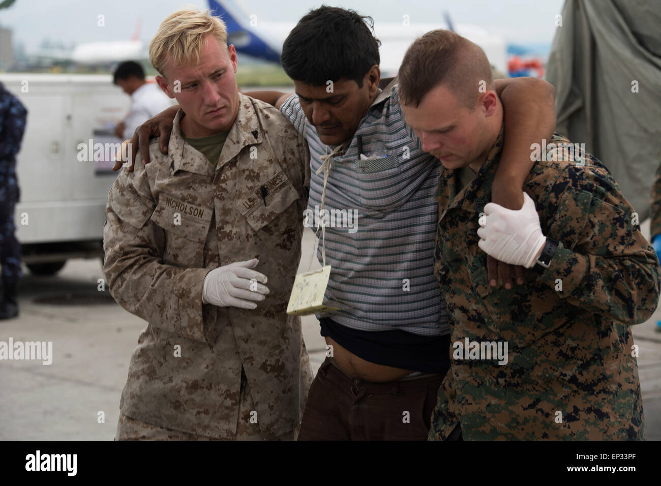 Kathmandu, Nepal. 13th May, 2015. U.S. Marines with Joint Task Force 505 help a man to a medical triage area setup at Tribhuvan International Airport May 12, 2015 in Kathmandu, Nepal. A 7.3 magnitude aftershock earthquake struck the kingdom following the 7.8 magnitude earthquake on April 25th. Stock Photo