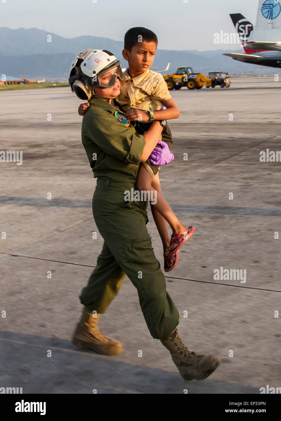 Kathmandu, Nepal. 13th May, 2015. U.S. Marine Sergeant  A. B. Manning from Joint Task Force 505 carries a young earthquake victim to a medical triage area at Tribhuvan International Airport May 12, 2015 in Kathmandu, Nepal. A 7.3 magnitude aftershock earthquake struck the kingdom following the 7.8 magnitude earthquake on April 25th. Stock Photo
