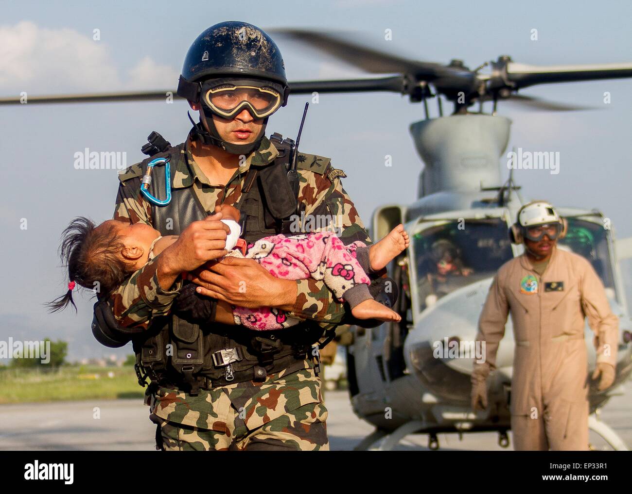 Kathmandu, Nepal. 13th May, 2015. A Nepalese soldier carries a young earthquake victim from a U.S Marine Corps helicopter to a medical triage area setup at Tribhuvan International Airport May 12, 2015 in Kathmandu, Nepal. A 7.3 magnitude aftershock earthquake struck the kingdom following the 7.8 magnitude earthquake on April 25th. Stock Photo