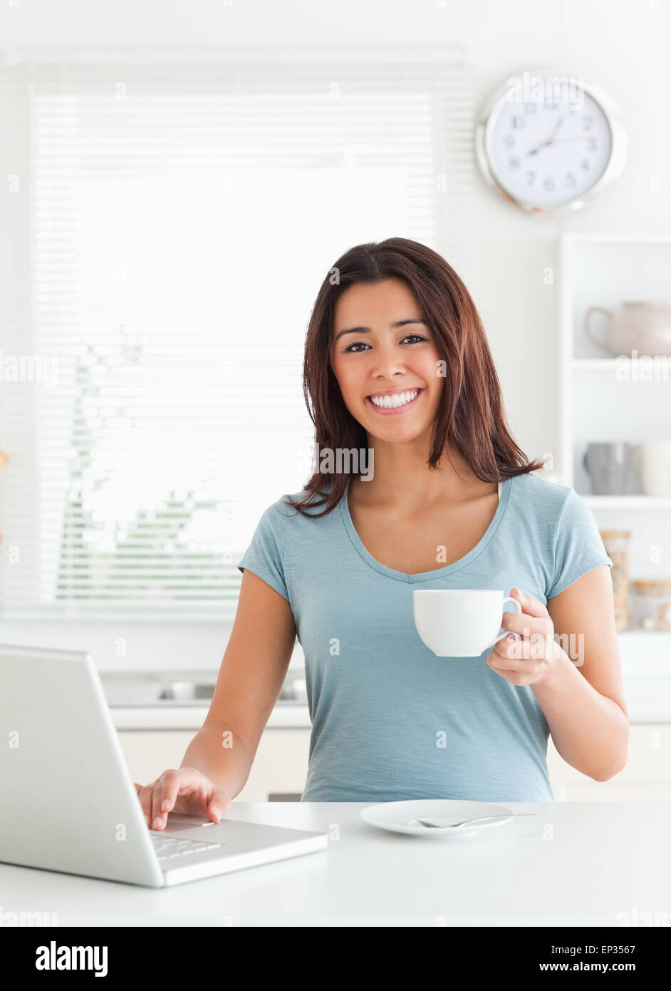 Attractive woman enjoying a cup of coffee while relaxing with her laptop Stock Photo