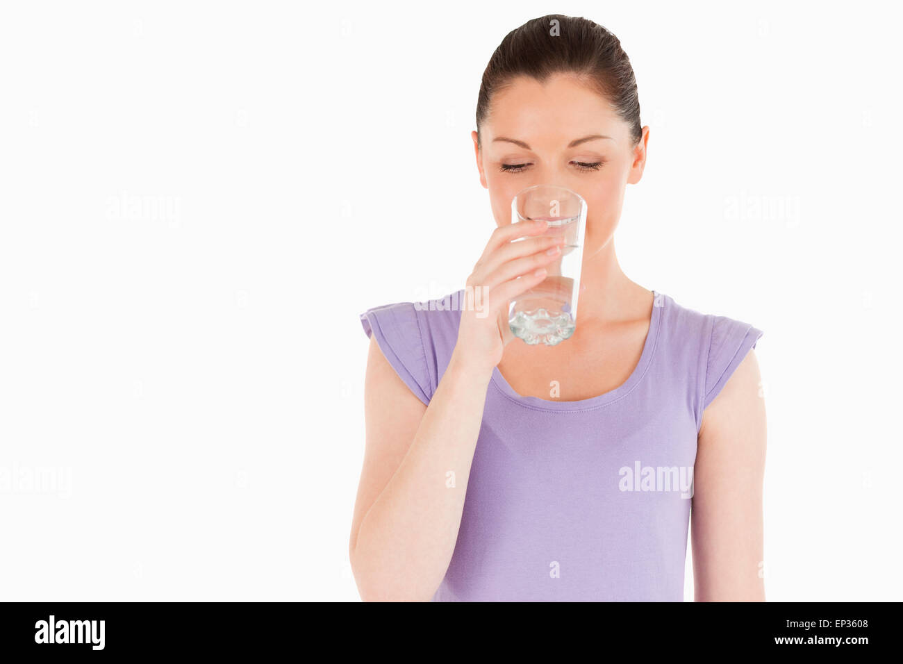 Beautiful woman drinking a glass of water while standing Stock Photo