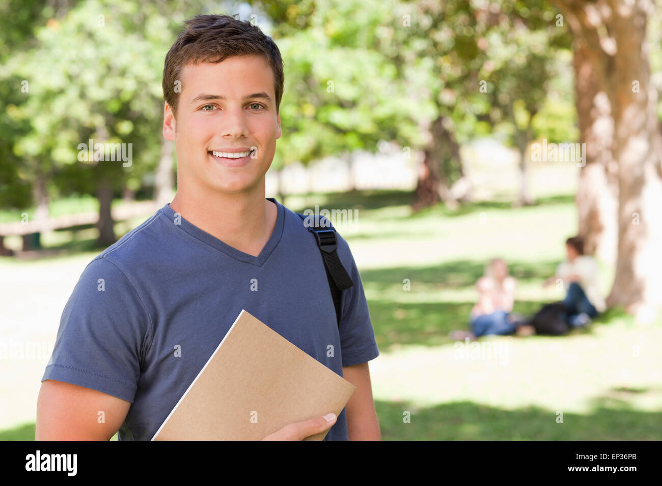 Portrait of a student smiling while holding a textbook Stock Photo - Alamy