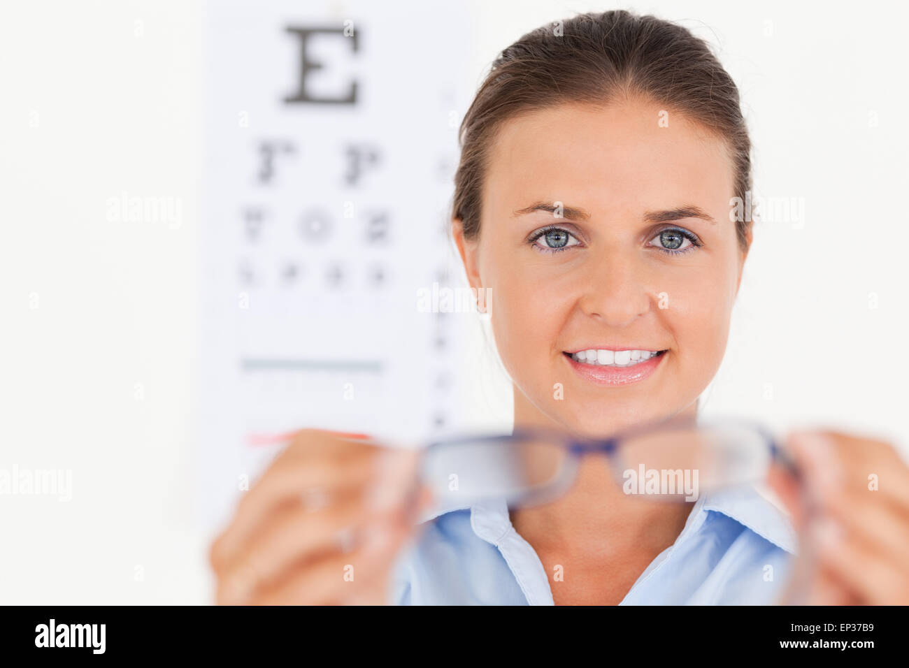 Portrait of a brunette eye specialist handing out glasses lookin Stock ...