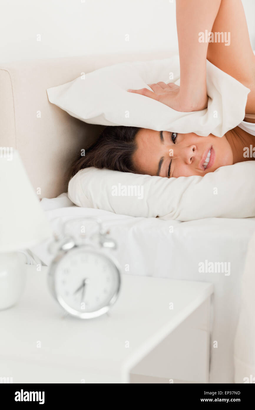 woman waking under sheet not wanting to hear alarm clock Stock Photo