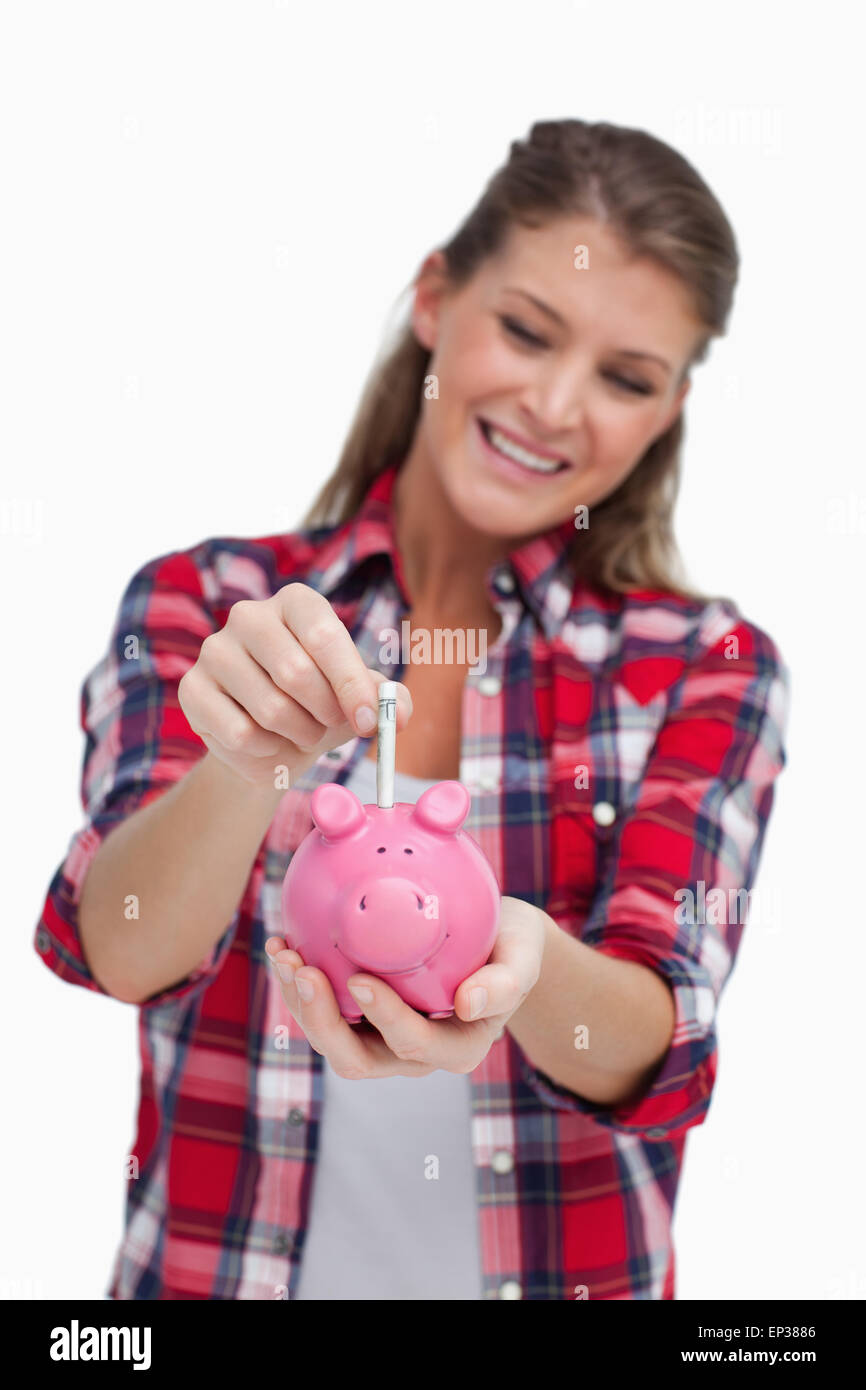 Portrait of a young woman putting a note a piggy bank Stock Photo - Alamy