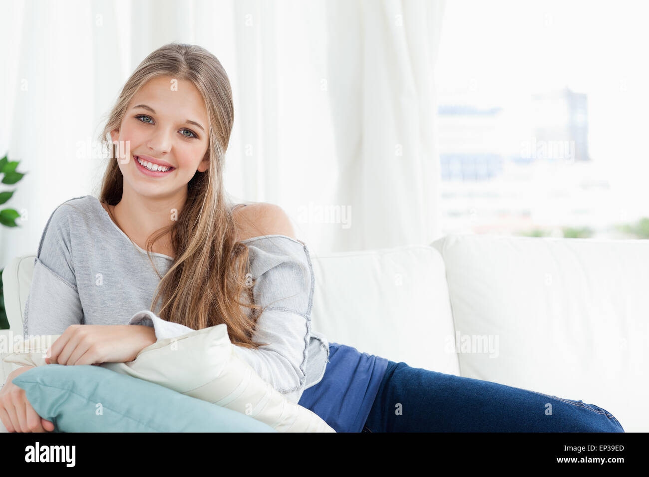 Smiling girl lying on the couch looking at the camera Stock Photo - Alamy