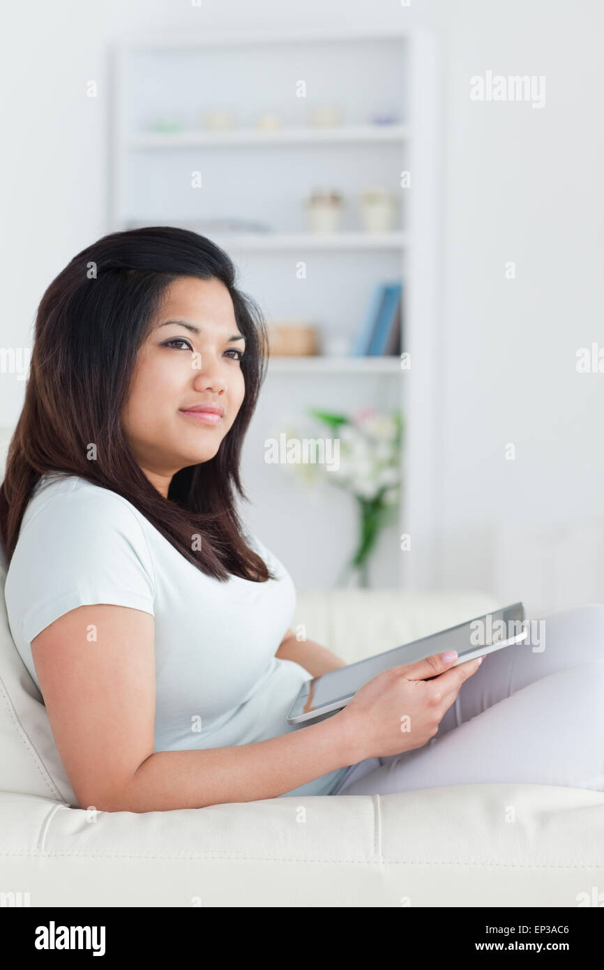 Woman sitting on a couch and holding a tablet Stock Photo - Alamy