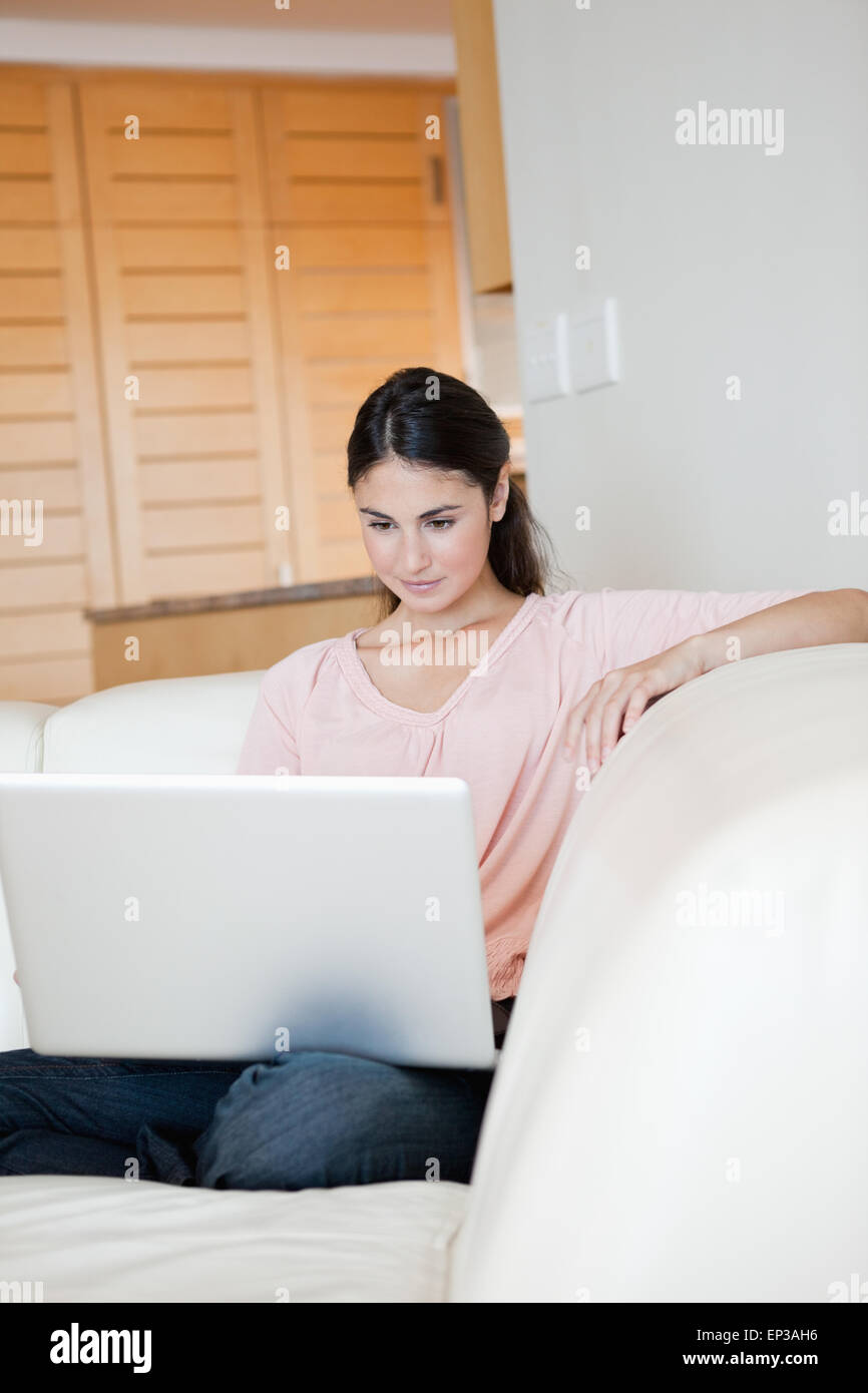 Woman using a laptop while sitting on a sofa Stock Photo - Alamy