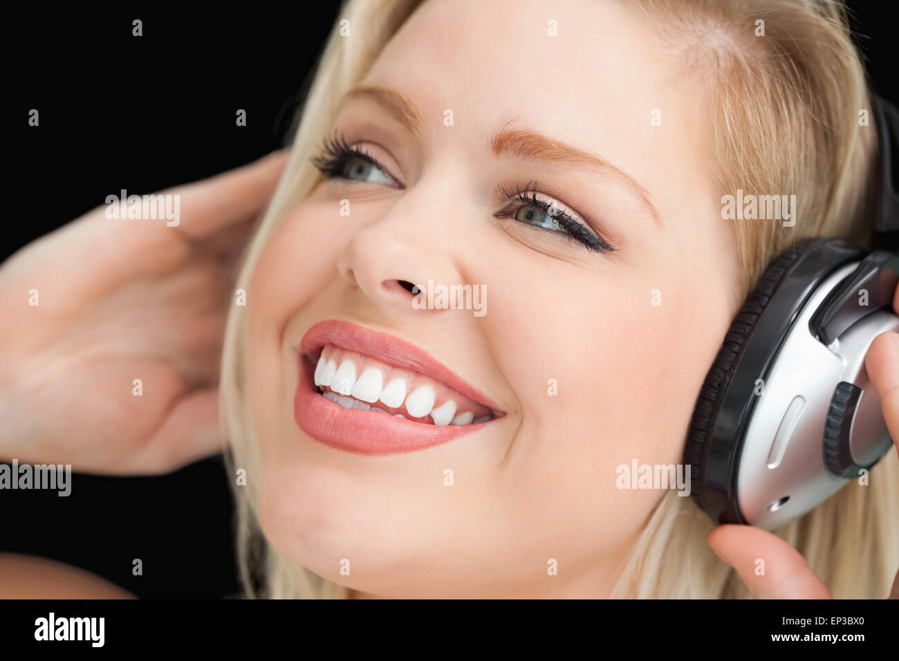 Happy blonde woman listening to music through headphones Stock Photo ...