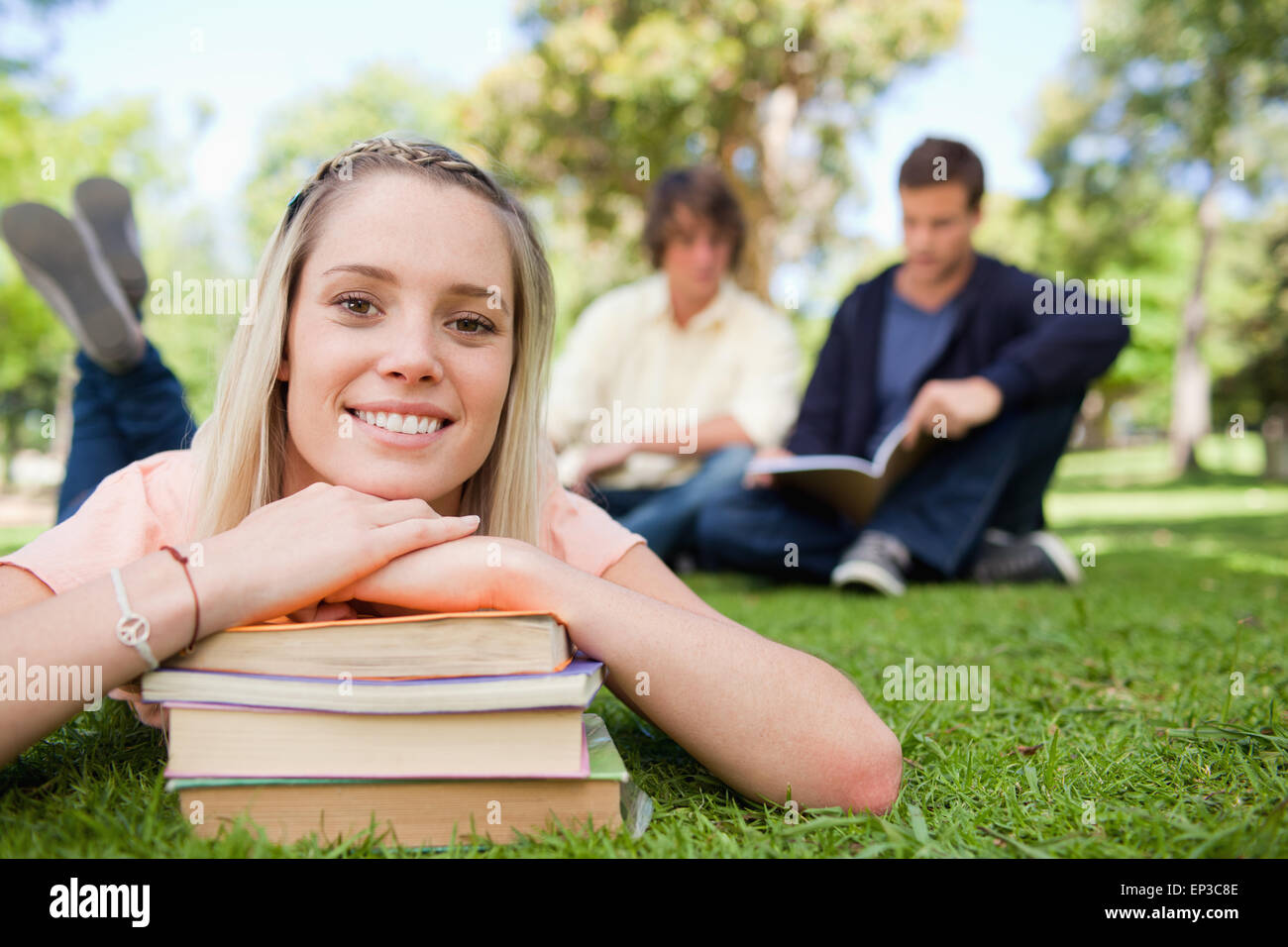 Portrait of a girl lying head on her books in a park Stock Photo - Alamy