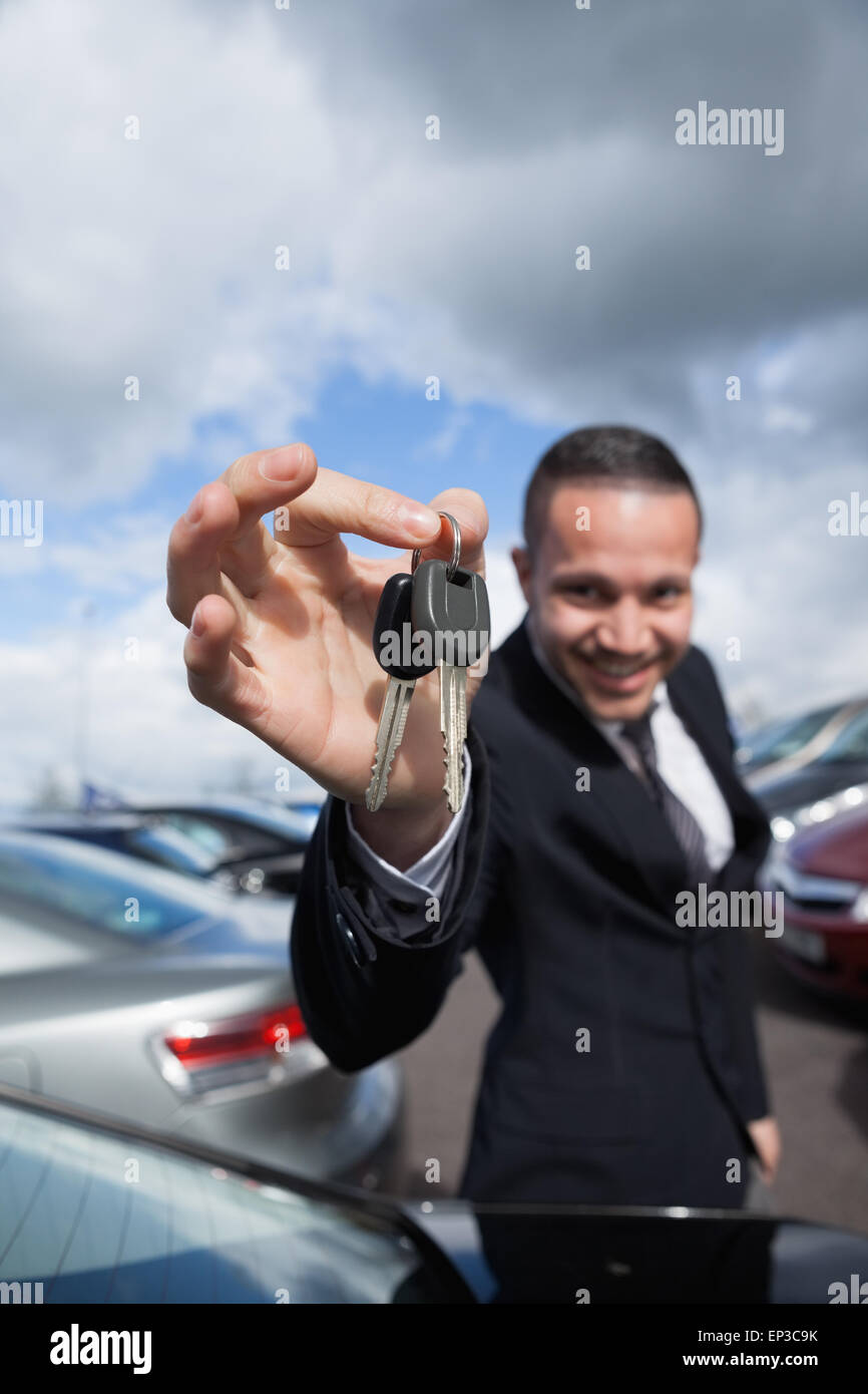 happy dealer holding car keys by his fingertips Stock Photo - Alamy