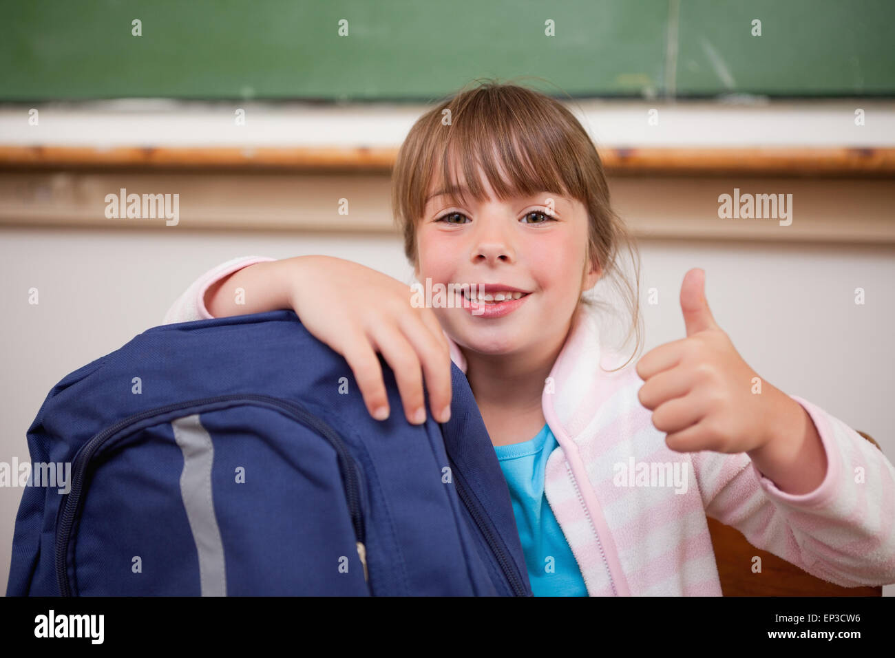 Smiling schoolgirl posing with a bag and the thumb up Stock Photo - Alamy