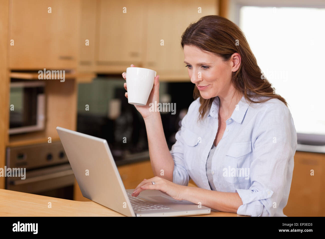 Woman drinking tea while on laptop Stock Photo - Alamy