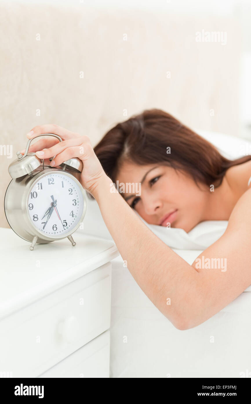 An alarm clock showing the time being silenced by a woman lying beside