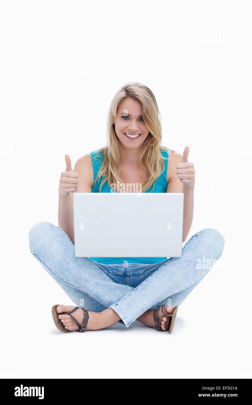 A woman with her thumbs up is sitting on the ground with a laptop Stock ...