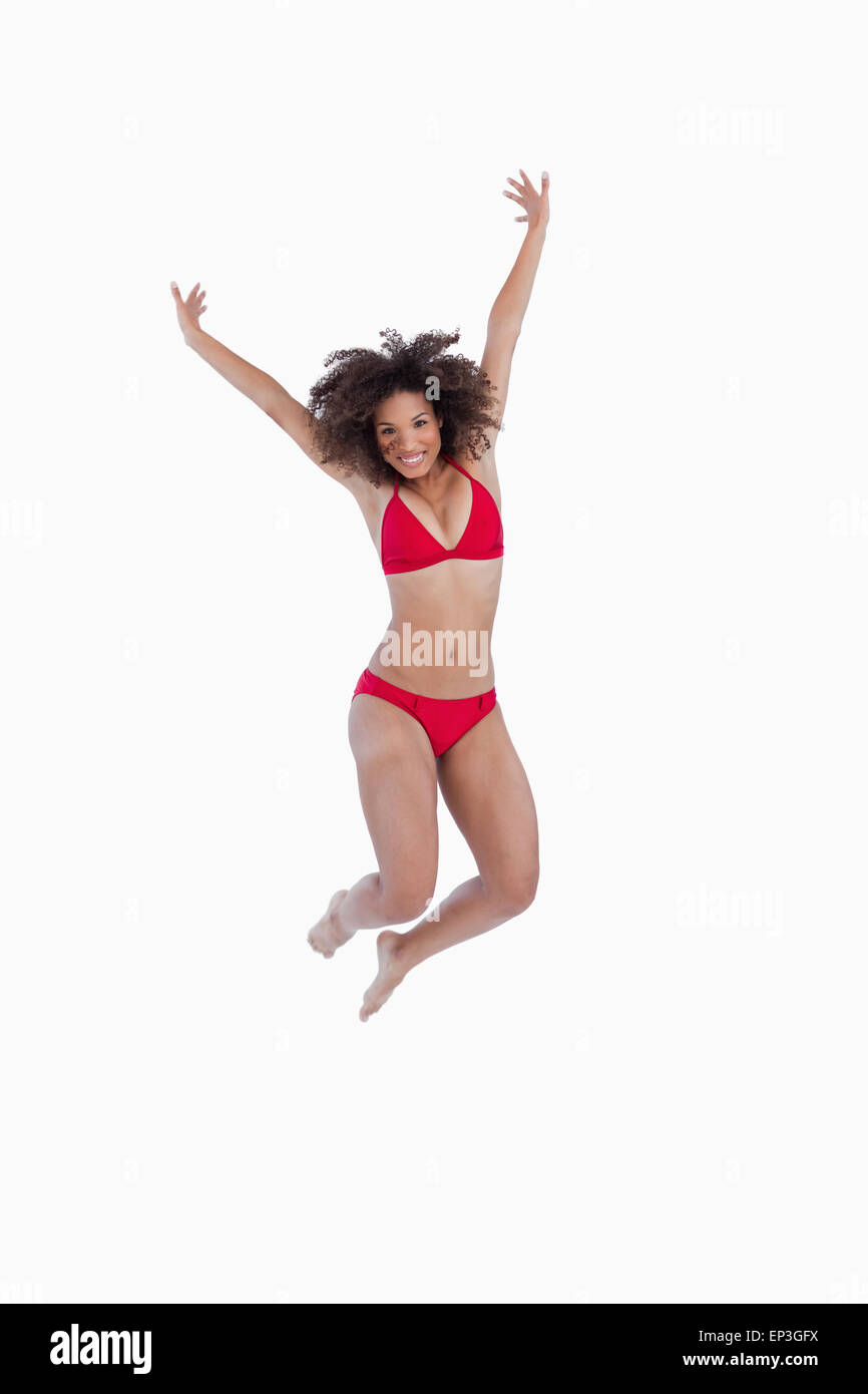 Happy brunette woman jumping while raising her arms Stock Photo