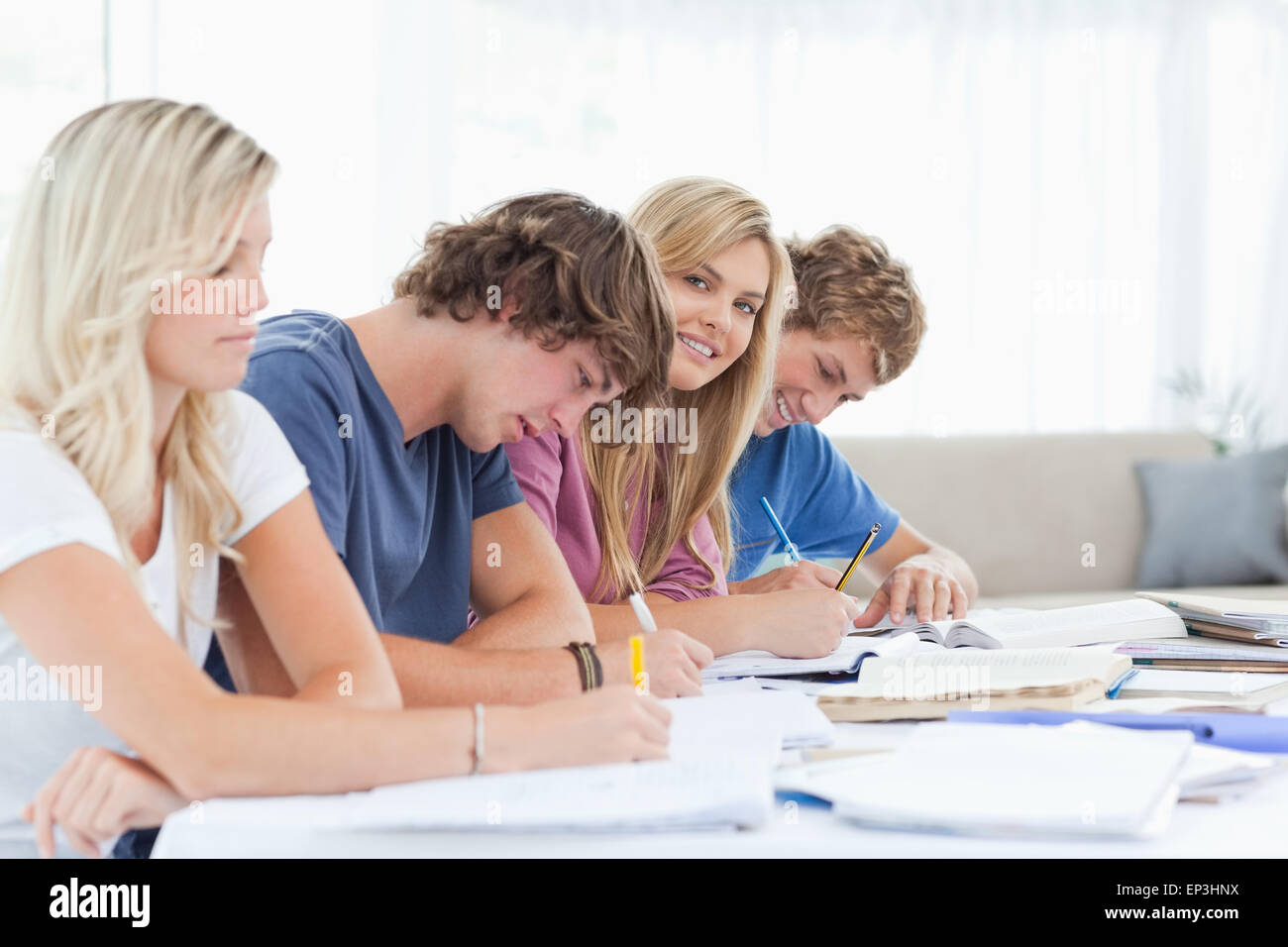 A smiling girl looks at the camera while she sits with students Stock ...