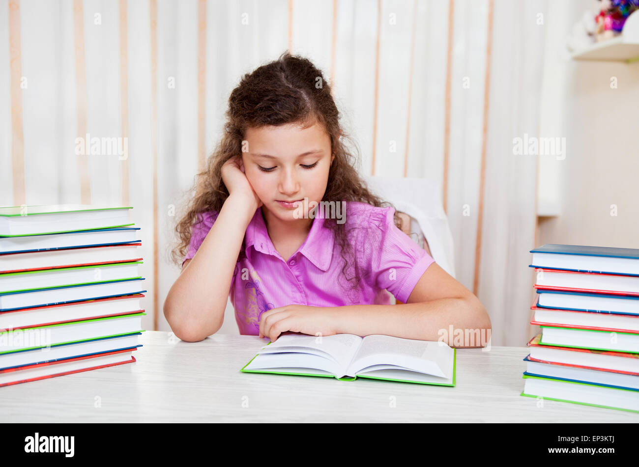 Little brunette smiling girl with pile of books Stock Photo - Alamy