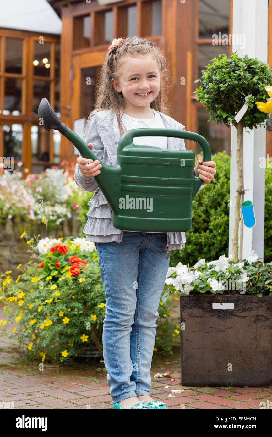 Little girl holding watering can while smiling Stock Photo - Alamy