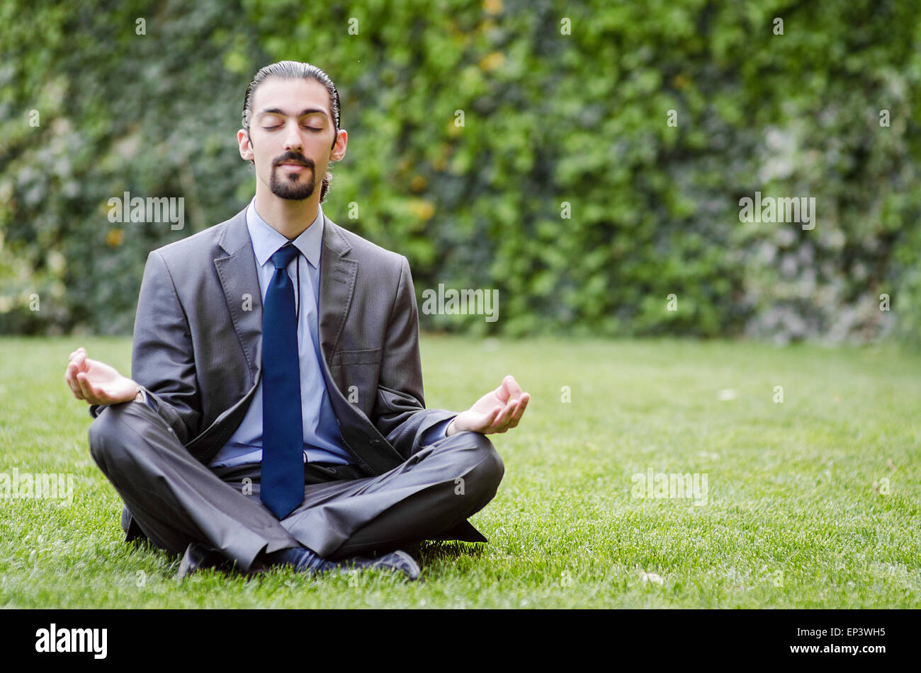 Young businessman meditating in the garden Stock Photo - Alamy