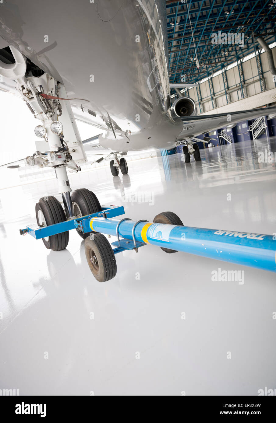 Airplane in a hanger ready to be pushed out with a tow bar connected to the nose landing gear Stock Photo