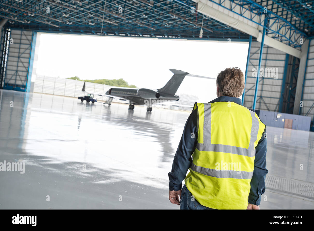 Ground crew approaching a private jet in a hanger being prepared for a flight Stock Photo