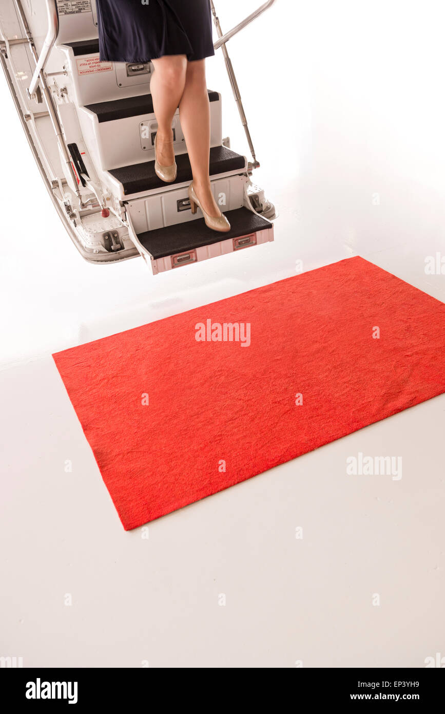Young woman on steps of a private airplane with a red carpet Stock