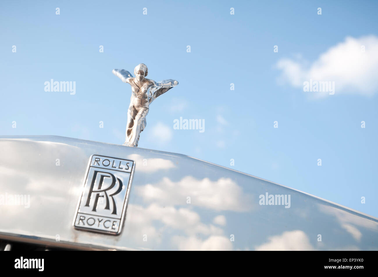 Spirit of Ecstasy on a Rolls-Royce car with blue sky and white clouds Stock Photo
