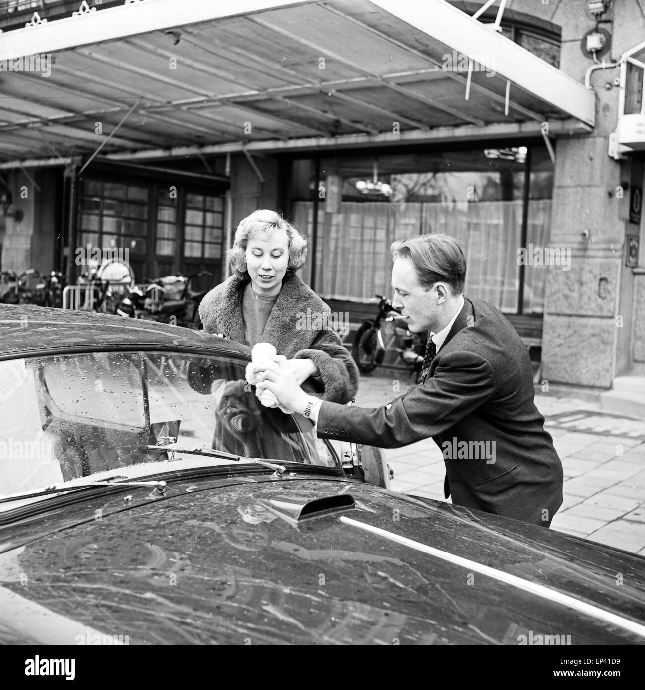 Der Jazz Posaunist Chris Barber putzt mit Ottilie Patterson, der Sängerin der Band, die Windschutzscheibe an ihrem Auto in Hambu Stock Photo