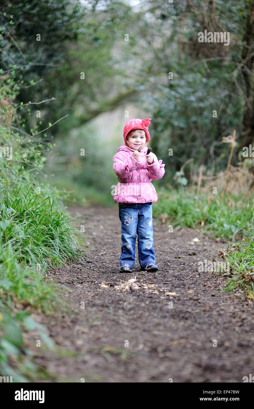 Girl standing on a path in the forest holding pine cones Stock Photo ...