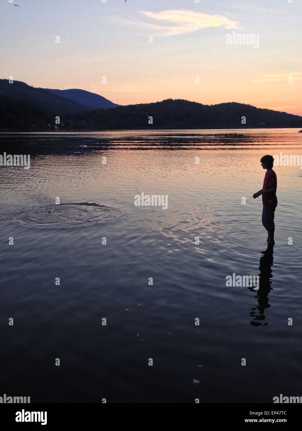 Silhouette of a boy fishing at night in mid summer, hof, norway Stock Photo