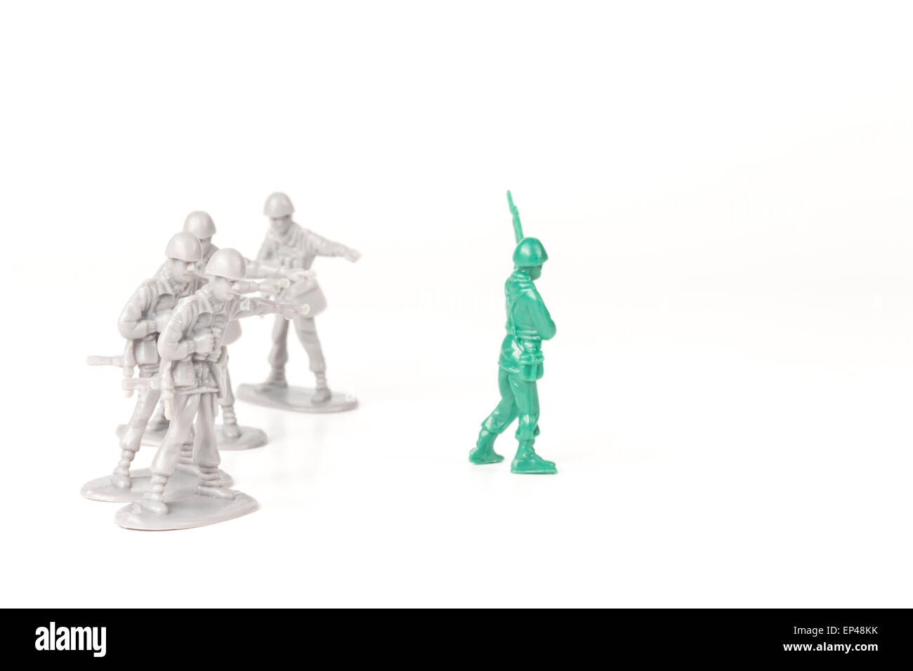 Gray toy soldiers pointing and bullying a green toy soldier Stock Photo