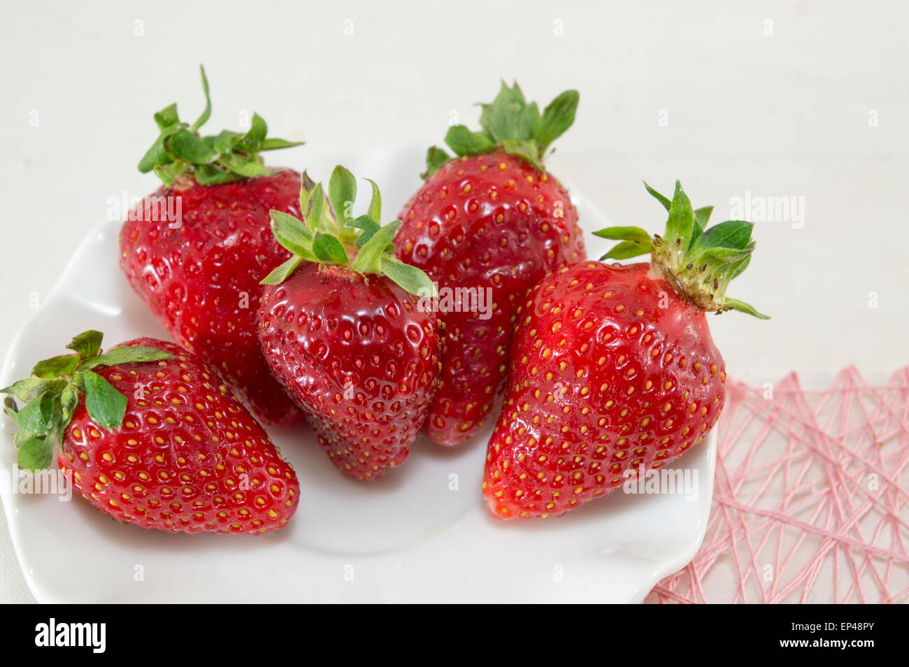 A fresh red ripe strawberry with green on a plate hi-res stock ...