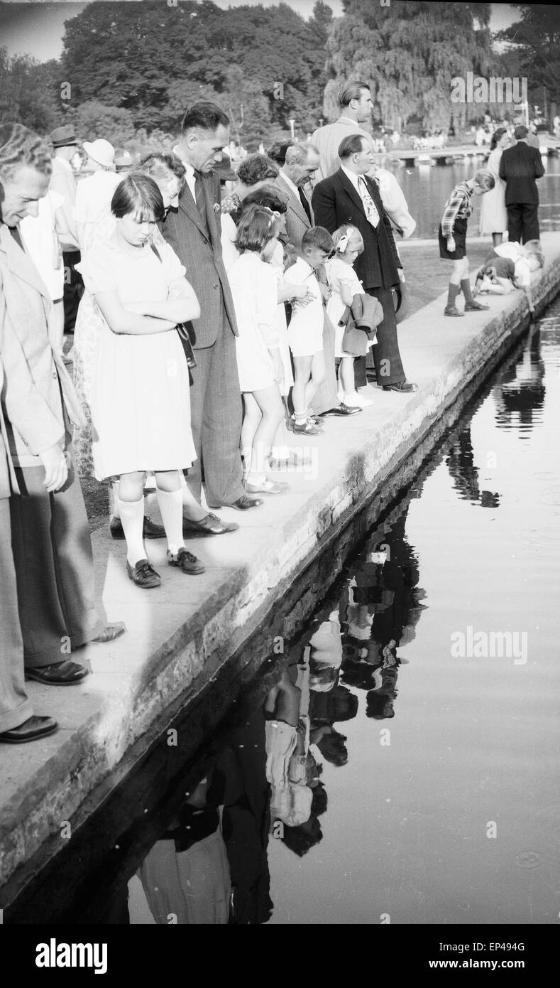 Besucher spiegeln sich im Weiher an der Sonnenuhr im Park Planten un Blomen in Hamburg, Deutschland 1950er Jahre. Visitors refle Stock Photo