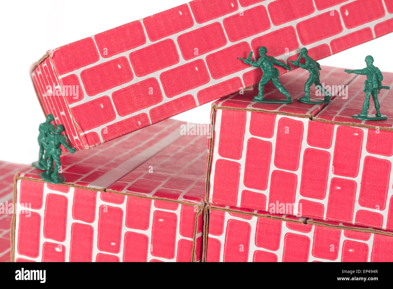 Green army men using teamwork to make progress up the toy brick stairs Stock Photo