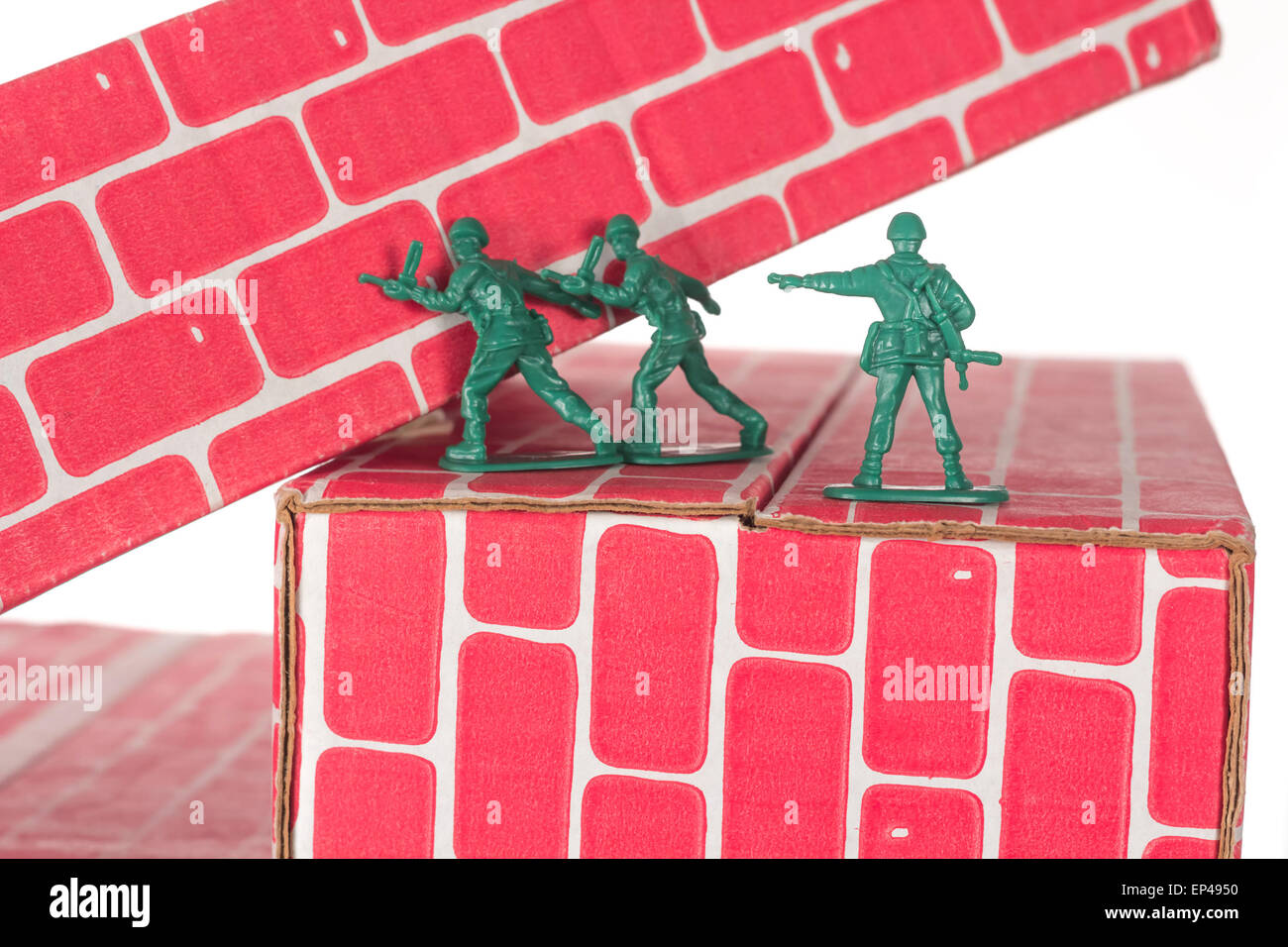 Green army men using teamwork to make progress up the toy brick stairs Stock Photo
