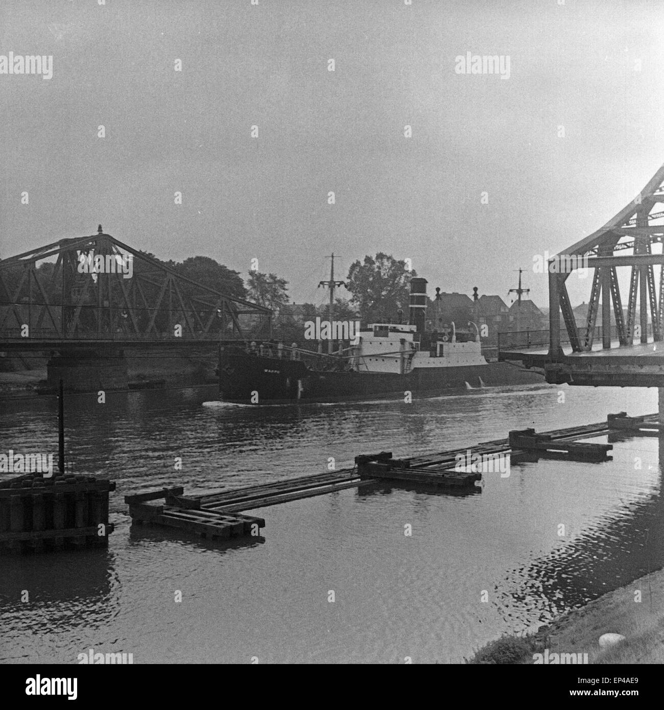 Ein Schiff fährt zwischen einer Drehbrücke hindurch, Deutschland 1950er Jahre. A ship passing a turn bridge, Germany 1950s. Stock Photo