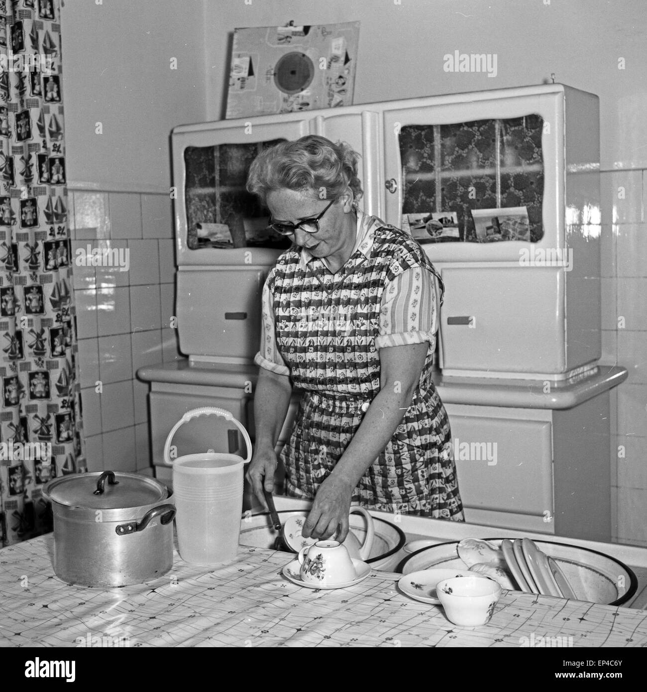 Eine Frau beim Spülen in ihrer Küche, Deutschland 1950er Jahre. A woman doing the dishwashing in her kitchen, Germany 1950s. Stock Photo